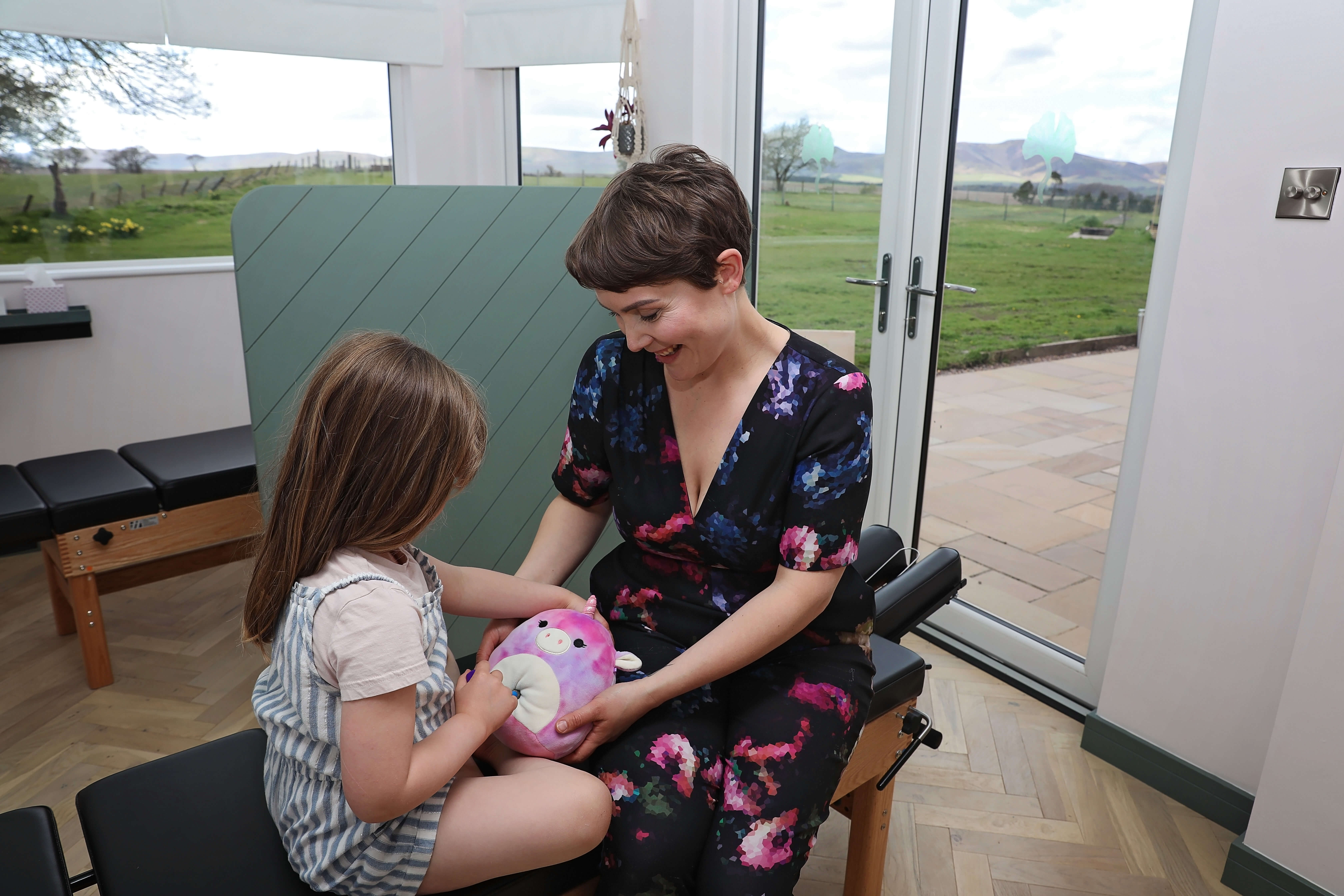 Chiropractor Naomi shows a young girl how to use an adjusting tool on her teddy